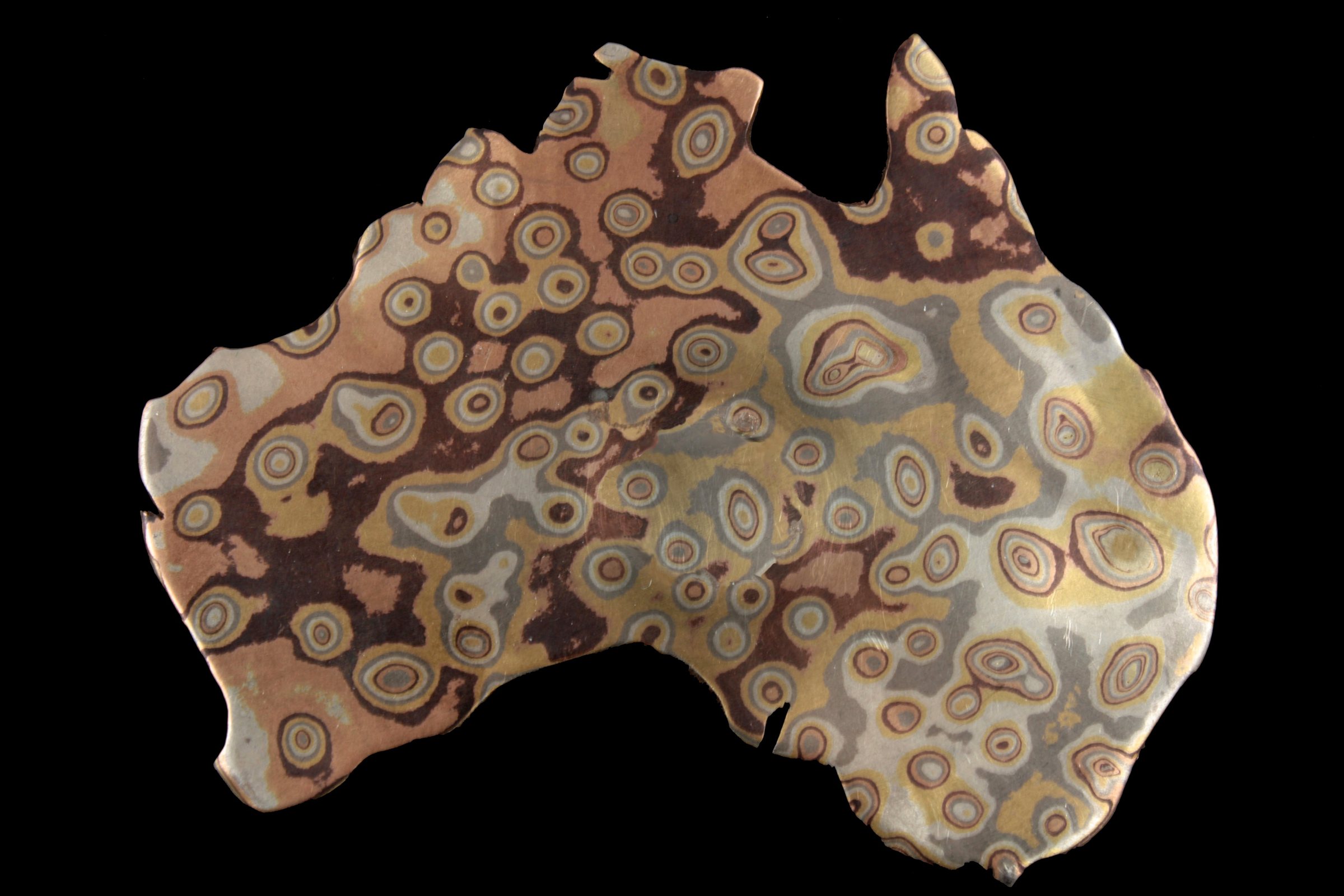 The map of Australia alone: a sheet of Mokume Gane metal patterned with rings and eyes in copper, silver and gold