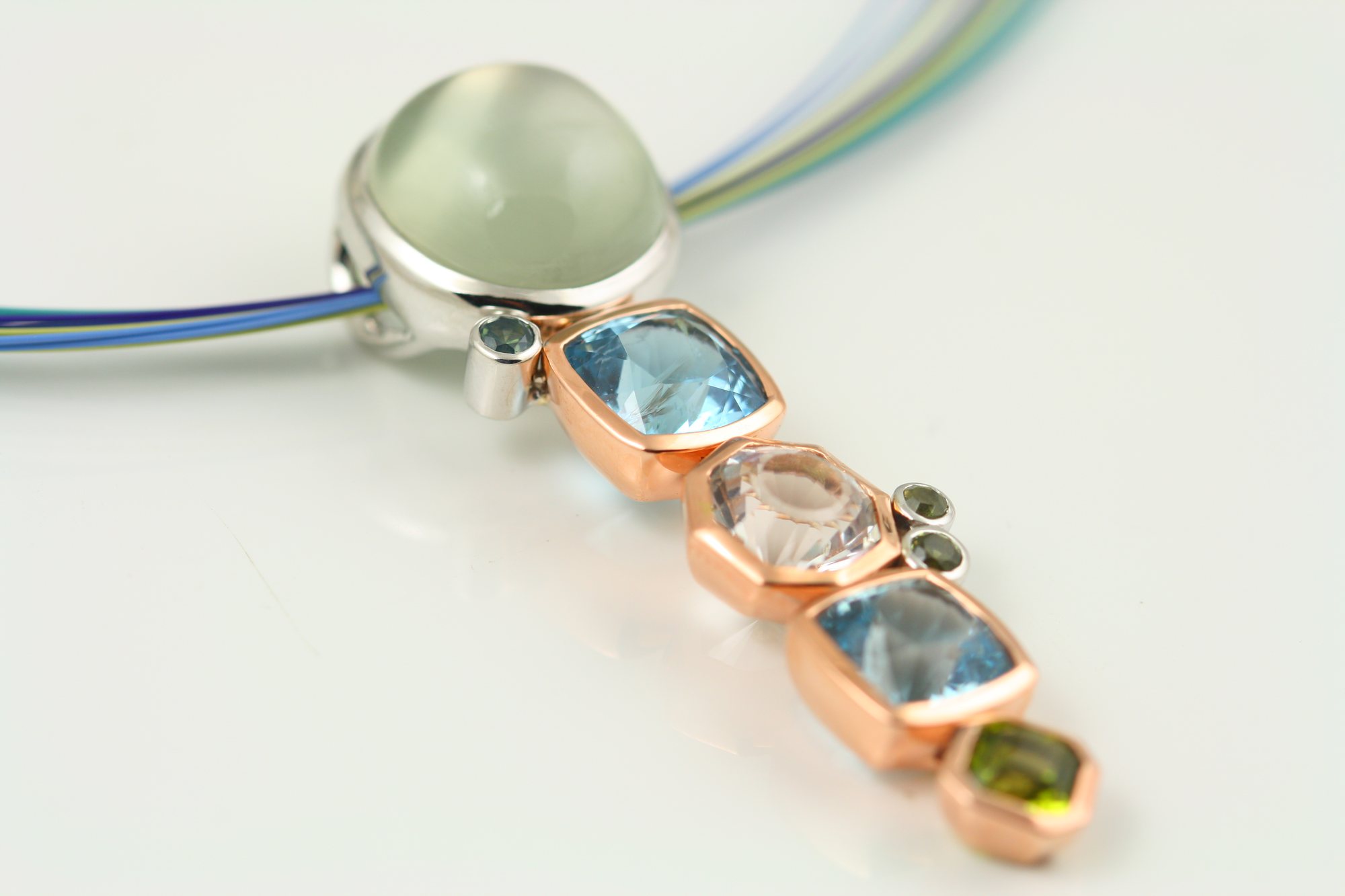 The same stones set in a line as a rose gold pendant on a cable