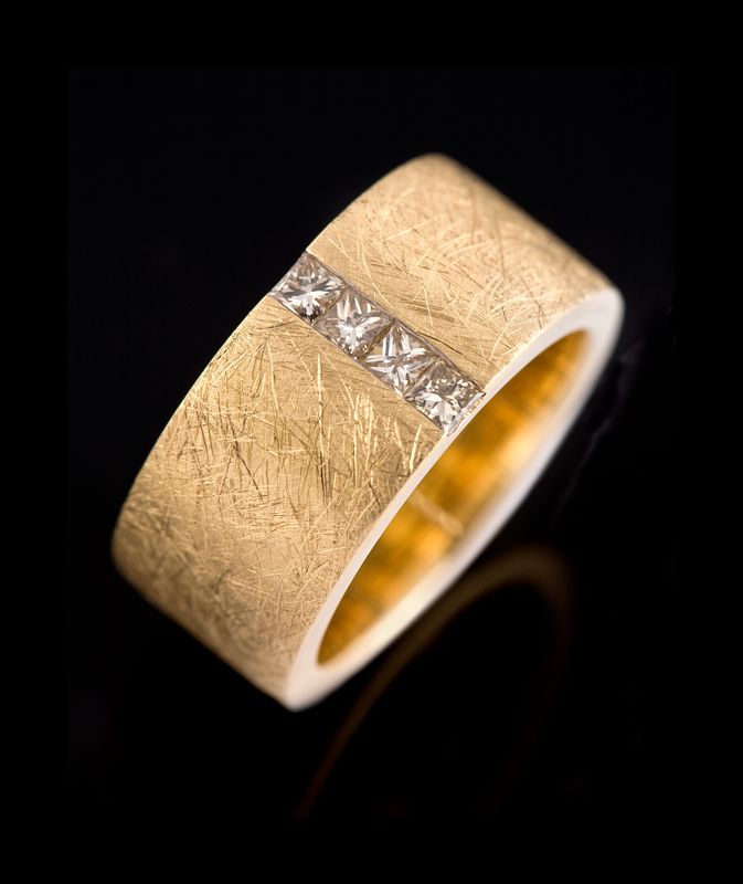 A wide scratch-textured yellow gold band with a channel of princess-cut diamonds across it