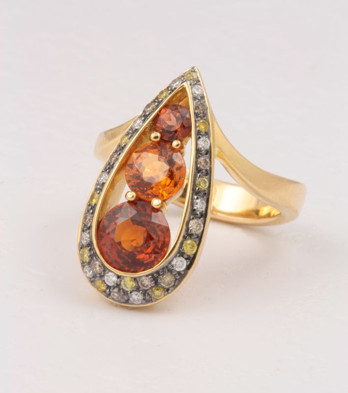 Gold ring with two orange spessartite garnets in a pear-shaped halo of champagne diamonds
