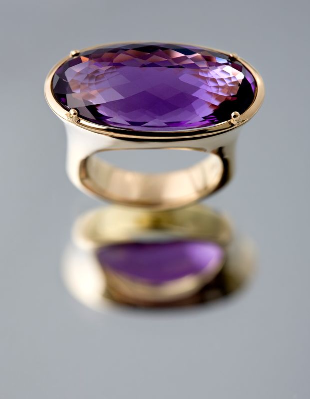 Ring with a large oval amethyst set east to west in yellow gold, standing on its reflection