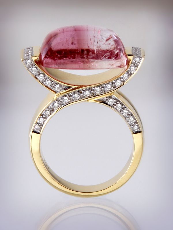 A yellow gold ring with a pink tourmaline cabochon held by two crossing diamond-set bands