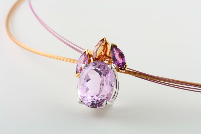 A lilac oval kunzite pendant topped with small pink and orange stones on a fine cable