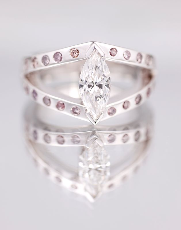 A large marquise diamond held between two chevron bands set with small pink diamonds, in white gold