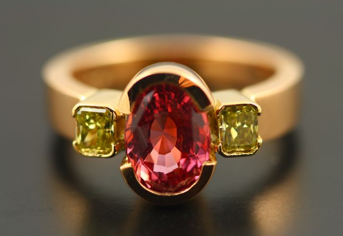 Padparadscha Sapphire and yellow diamond ring: a Padparadscha Sapphire set in 18 karat rose gold with two emerald cut yellow diamonds on either side of it