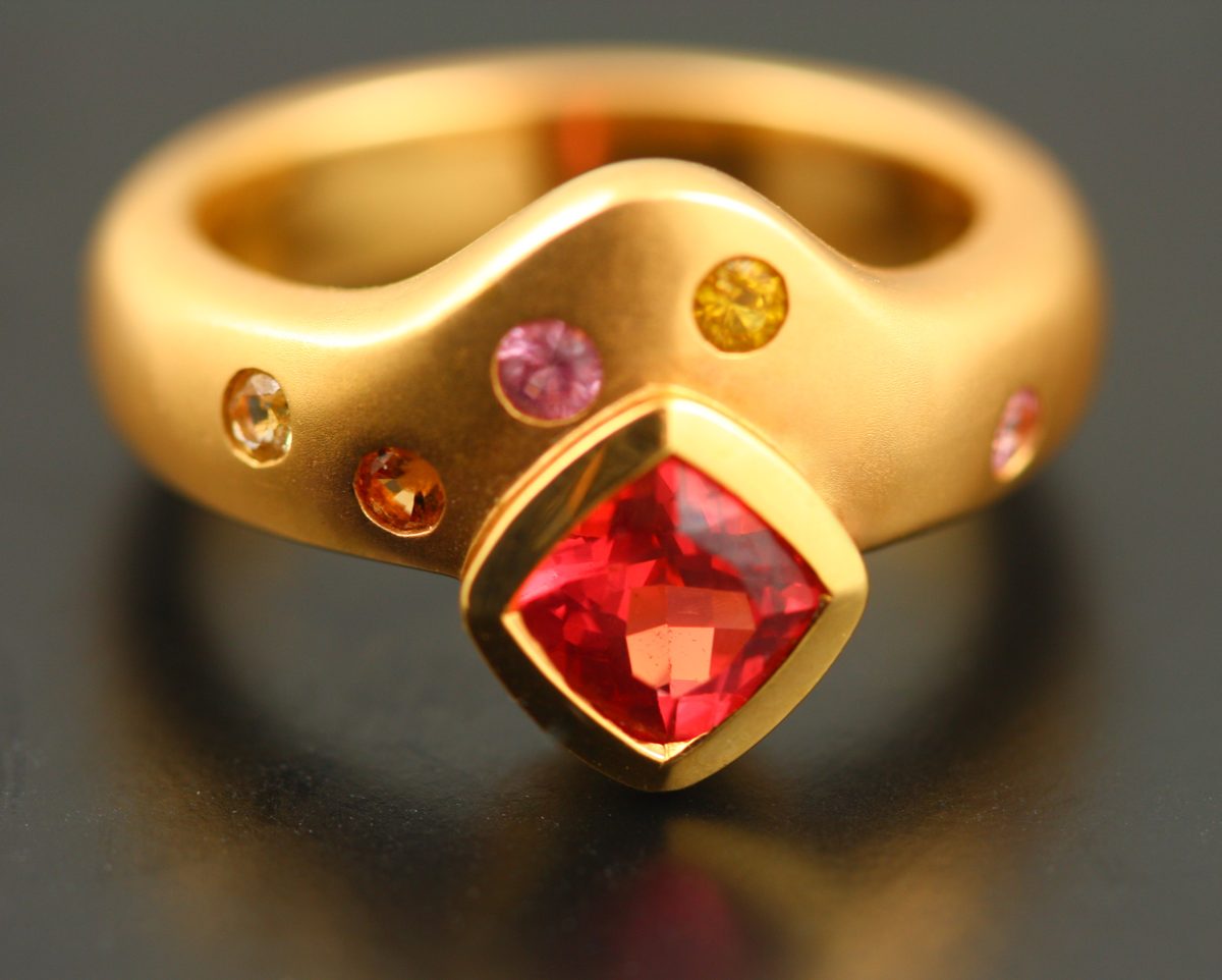Spinel scatter ring: a red Spinel with Sapphires in 18 karat yellow gold