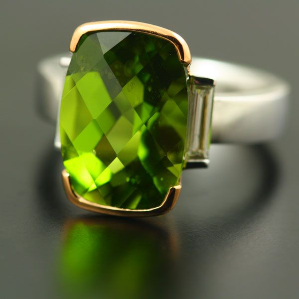 Peridot cushion ring: a Peridot with a baguette diamond in 18 karat white gold